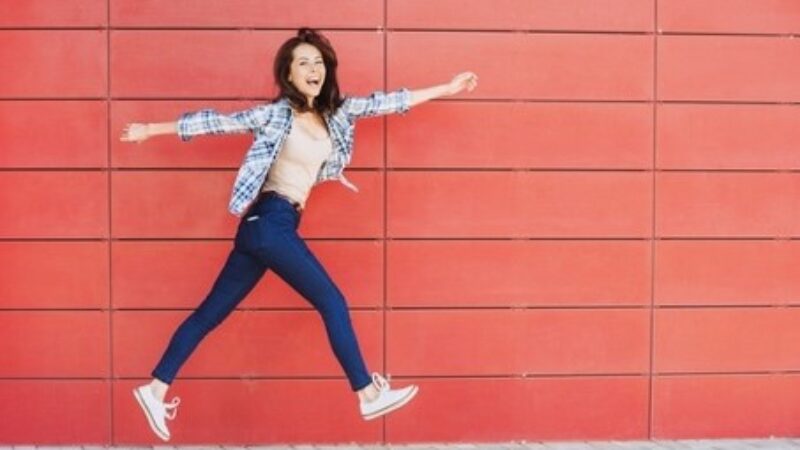 Woman enthusiastic jump red wall